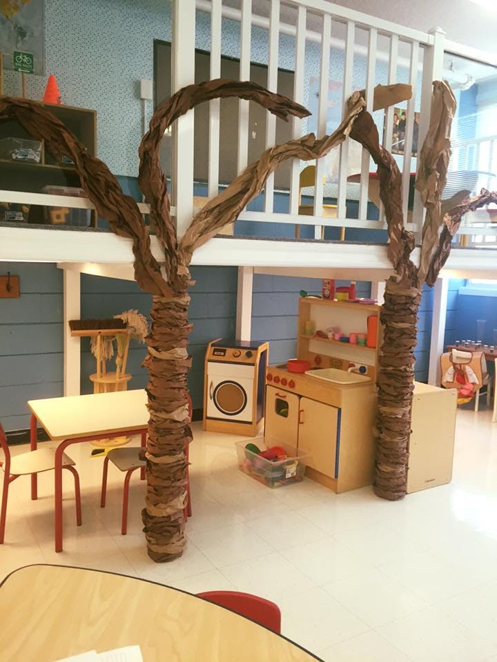 Playroom with two tree-like structures, a play kitchen, and a small table