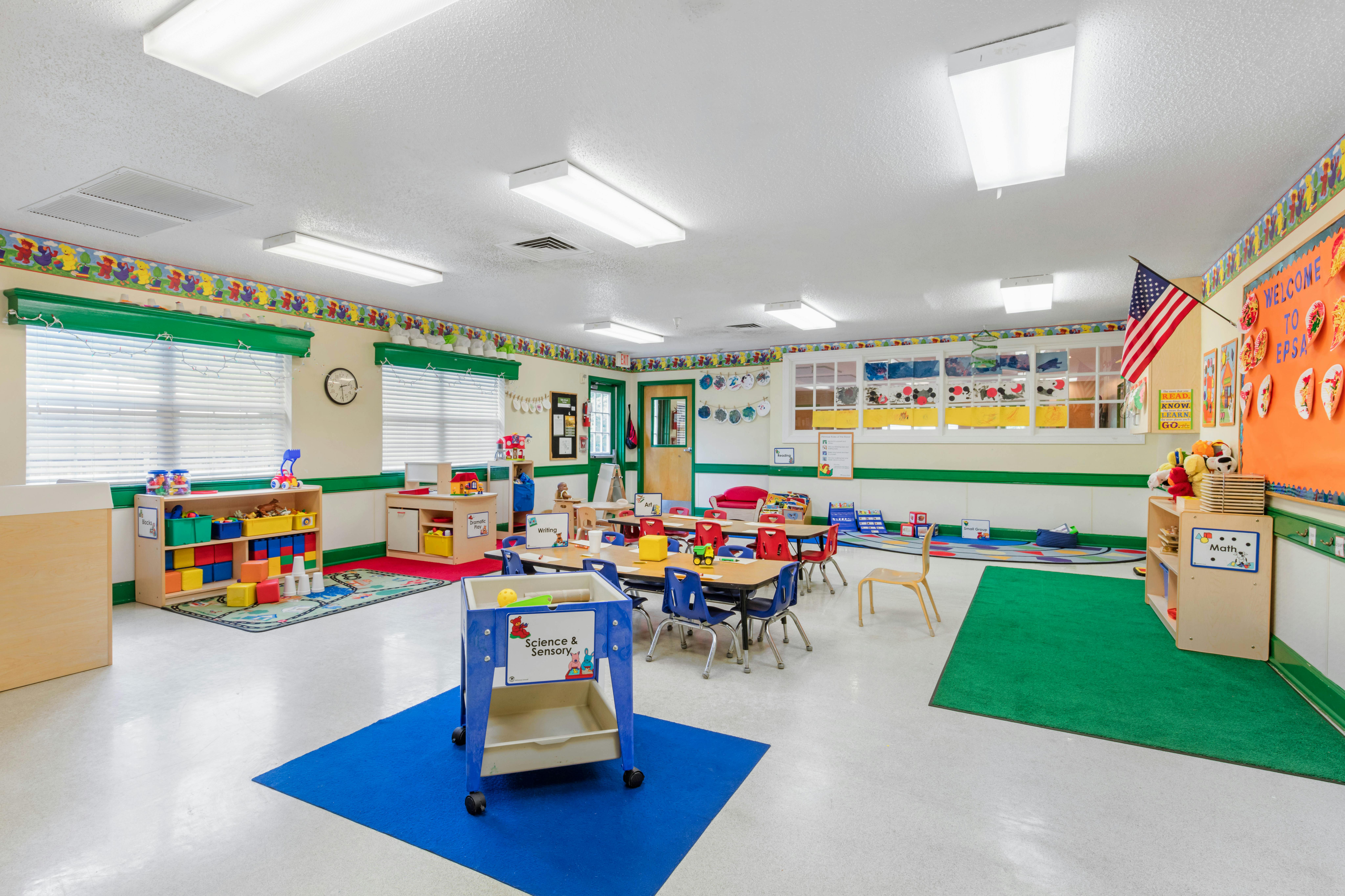 Colorful and organized classroom with tables, chairs, toys, and learning materials