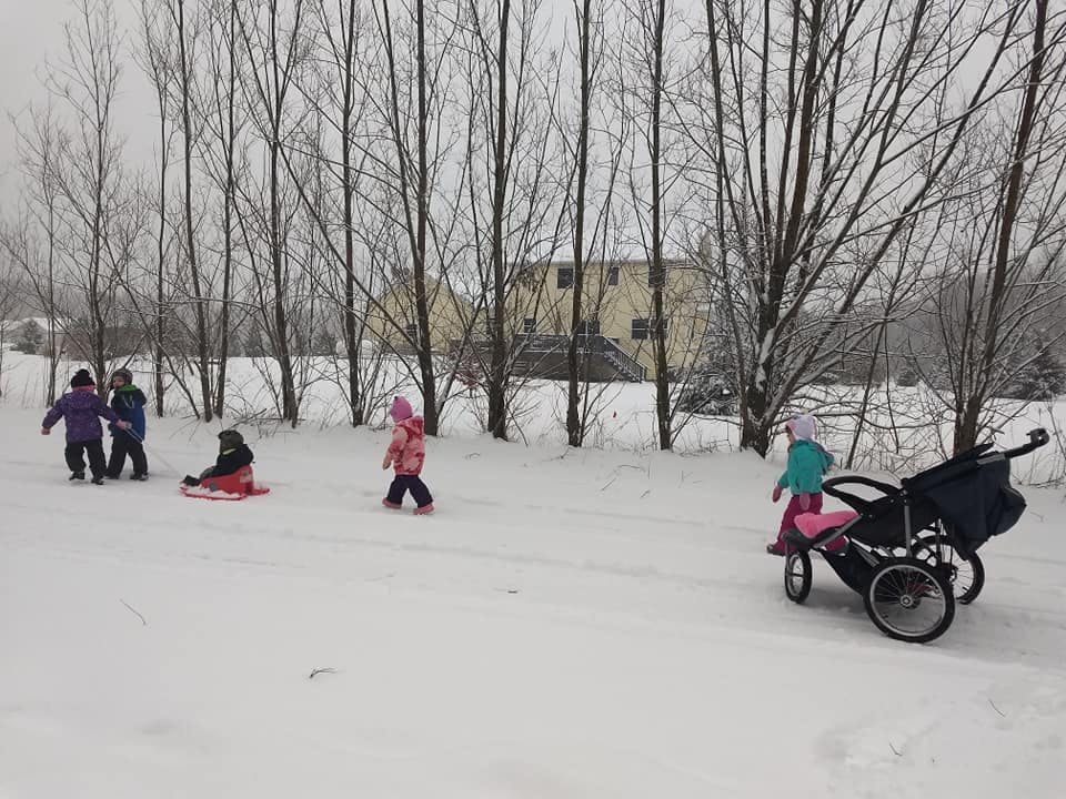 Children playing in the snow with a sled and a stroller