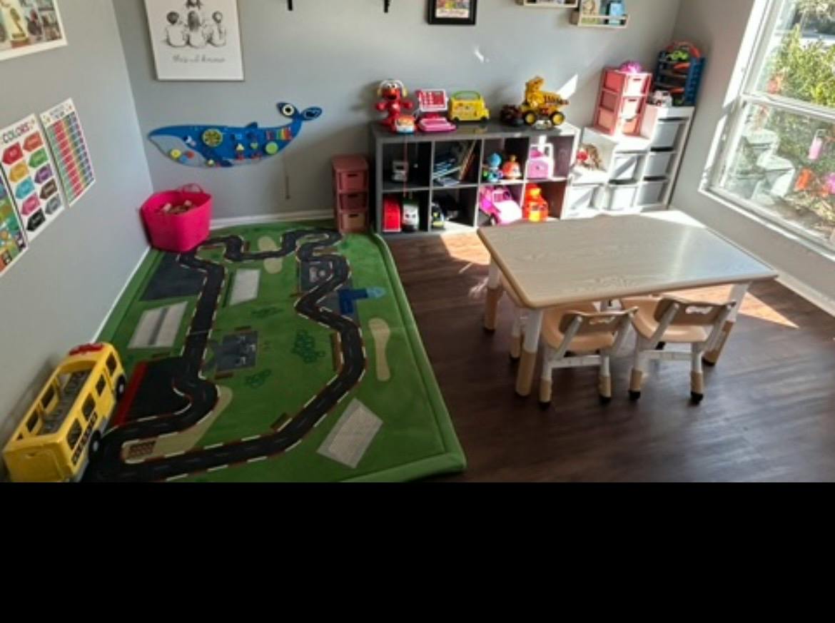Playroom with a small table, chairs, toy shelves, and a road-themed rug