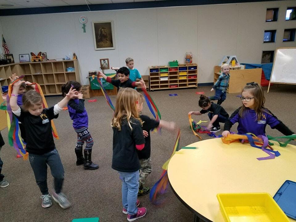 Children playing with colorful ribbons in a classroom
