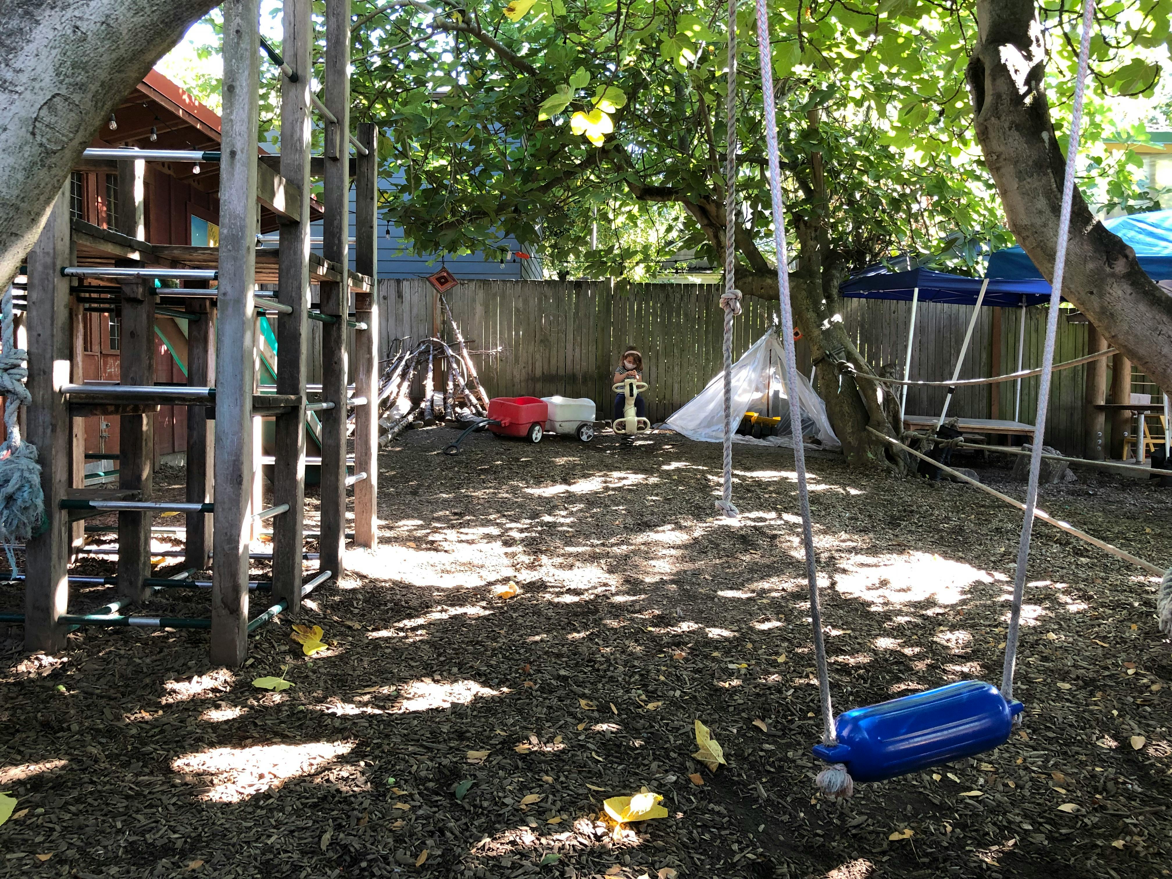 Outdoor play area with wooden climbing structure and swing