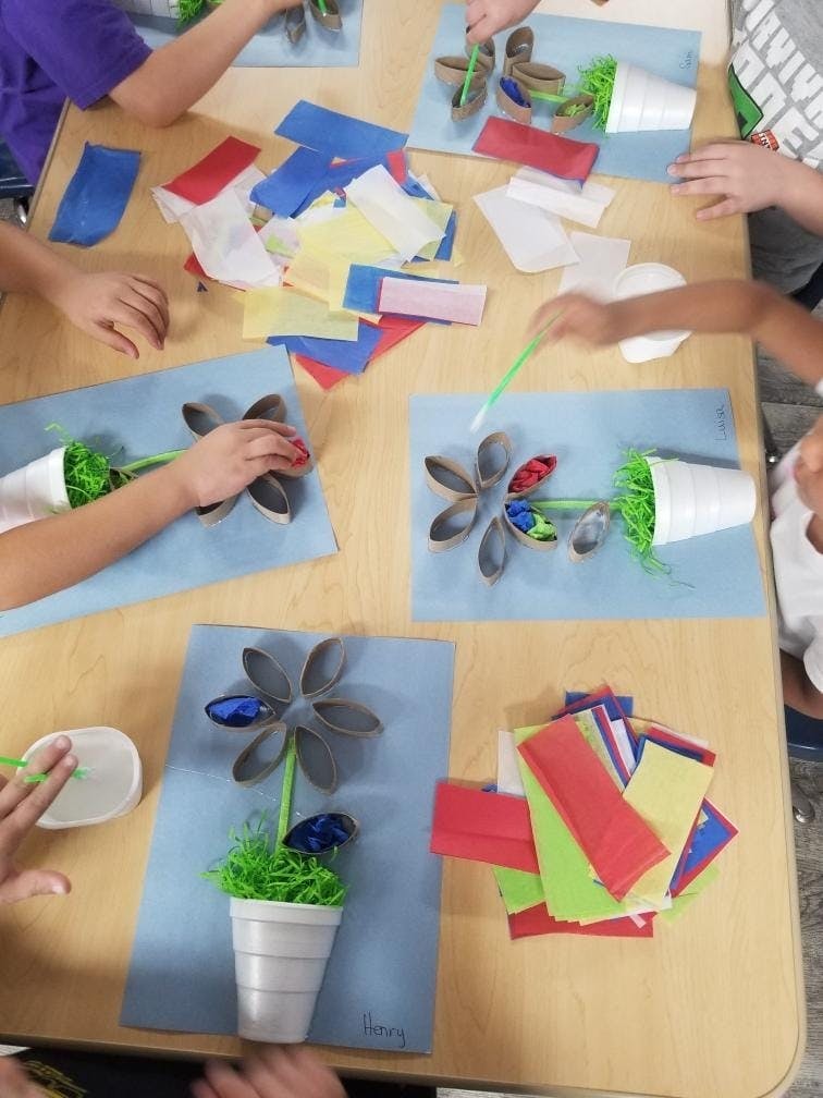 Children making flower crafts from paper and recycled materials