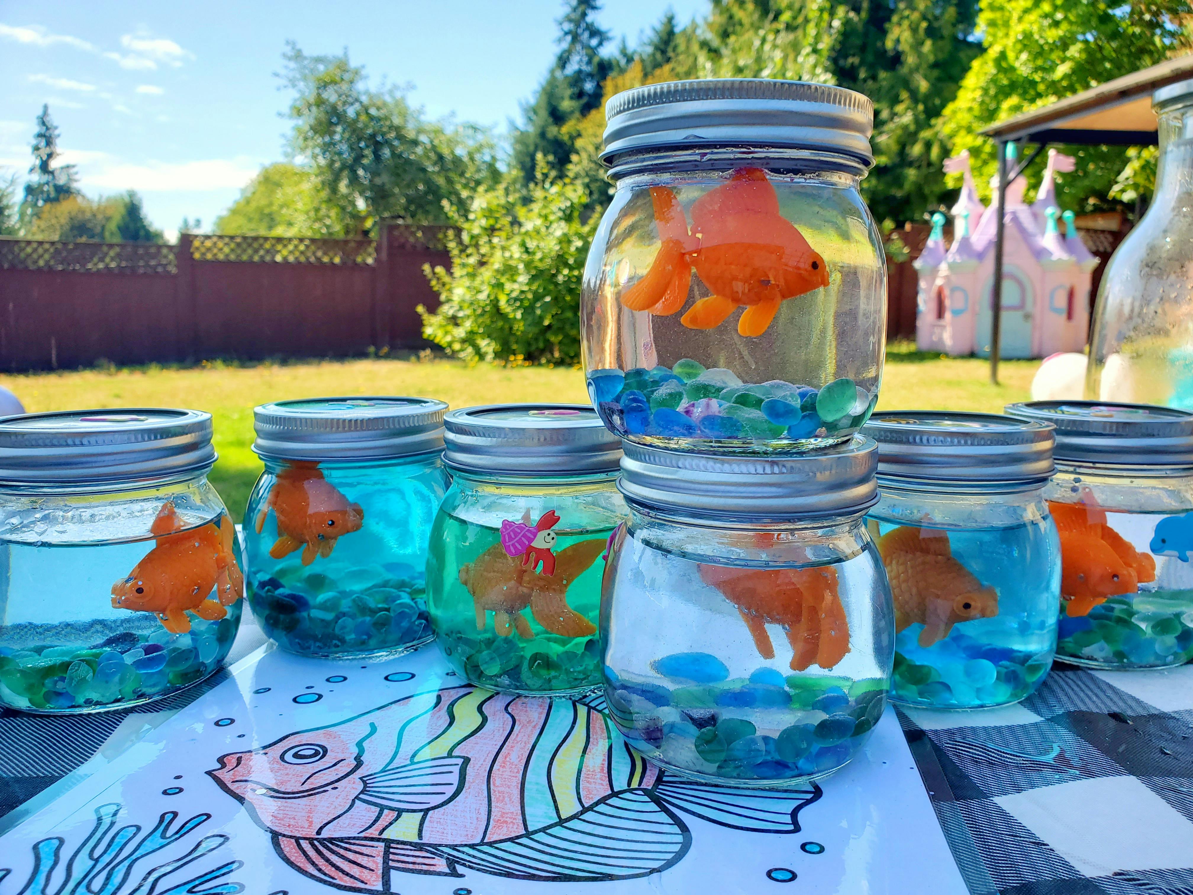 Mason jars with toy fish and colorful beads in water