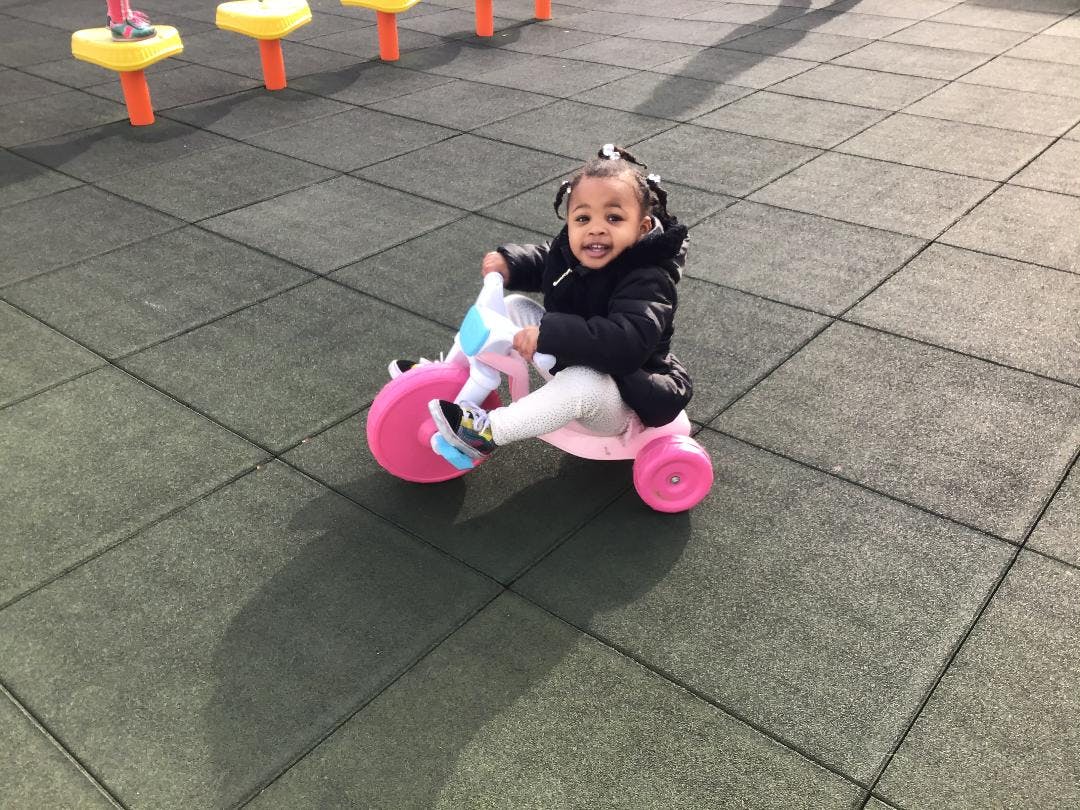 Child riding a pink tricycle on a playground