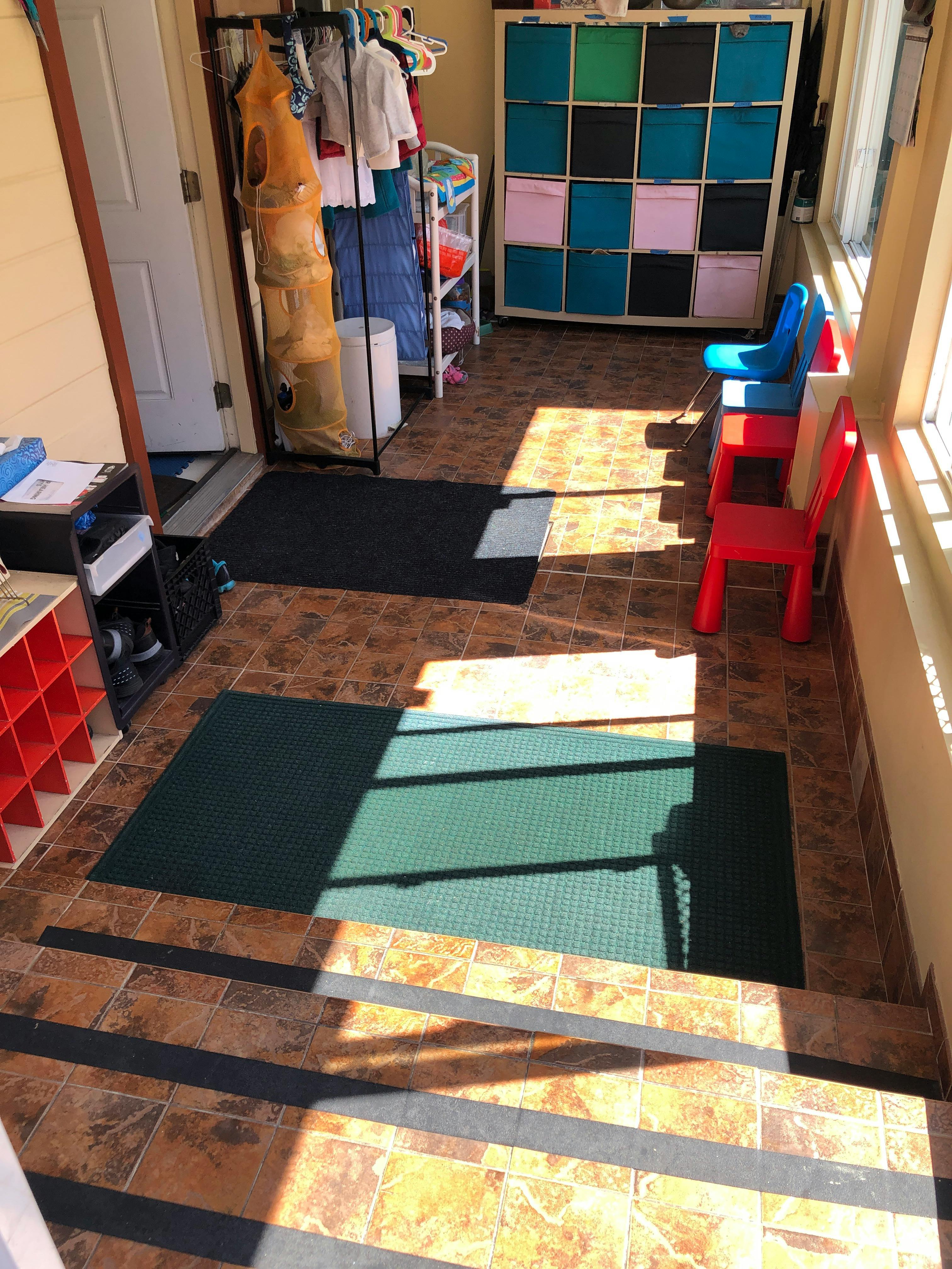 Room with tiled floor, storage unit, clothing rack, and small chairs