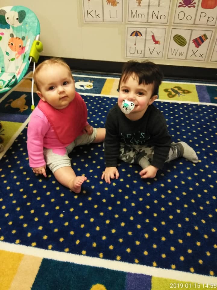 Two children sitting on a patterned rug