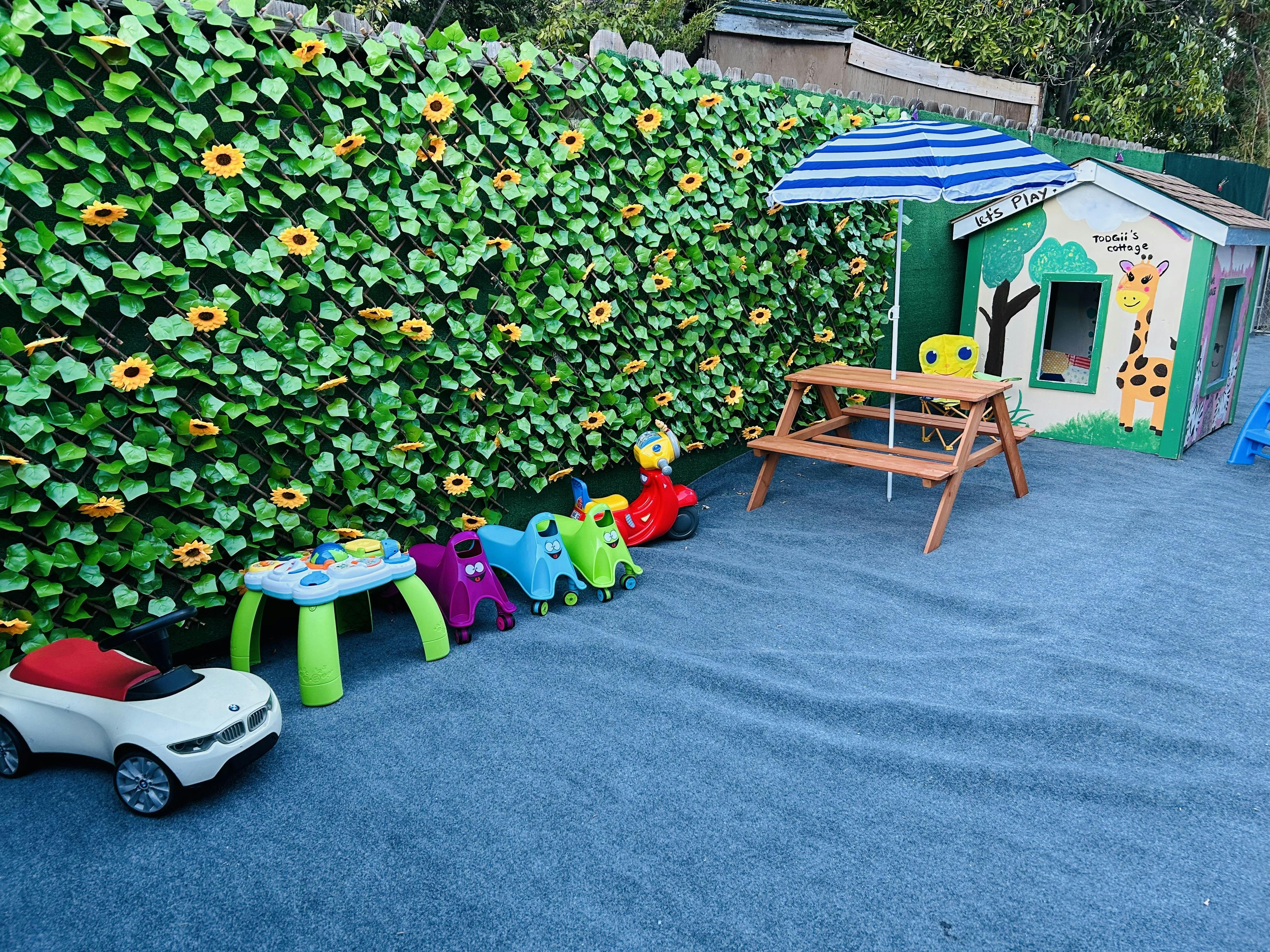 Children's play area with toys, picnic table, umbrella, and playhouse