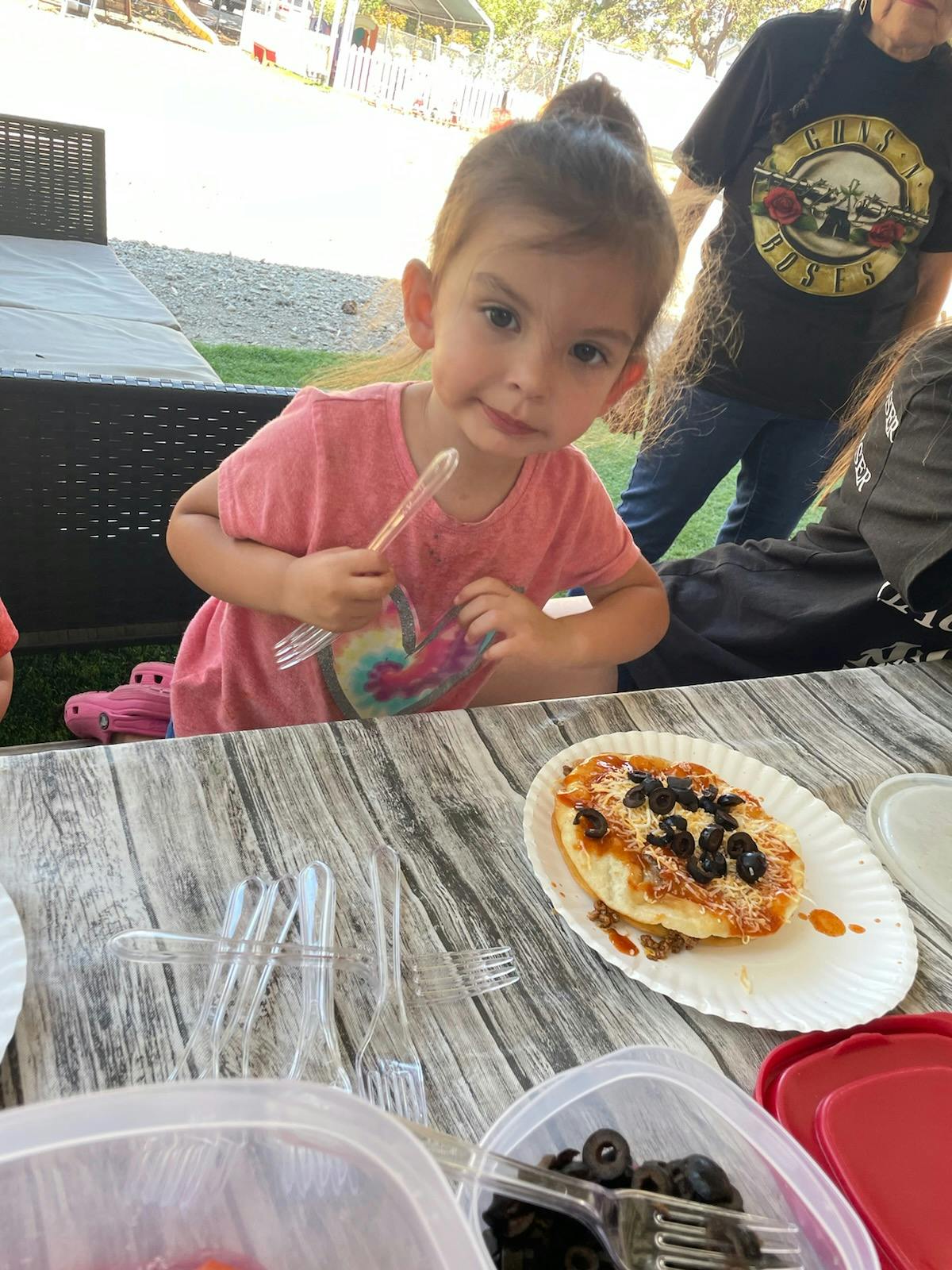 Child holding a fork at a table with food