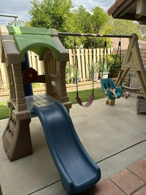 Plastic playground slide and swing set on a patio