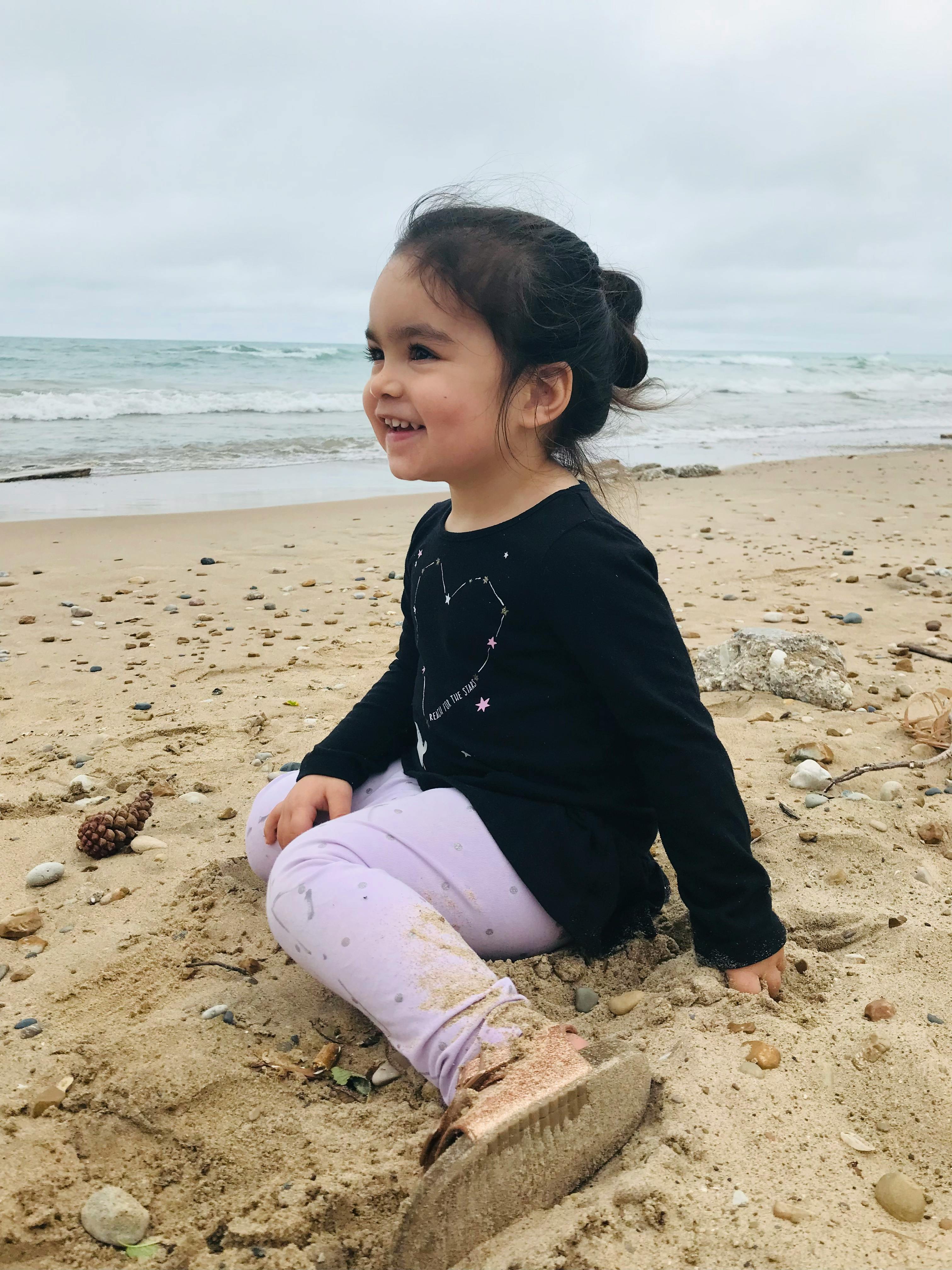 Child sitting on a sandy beach near the ocean