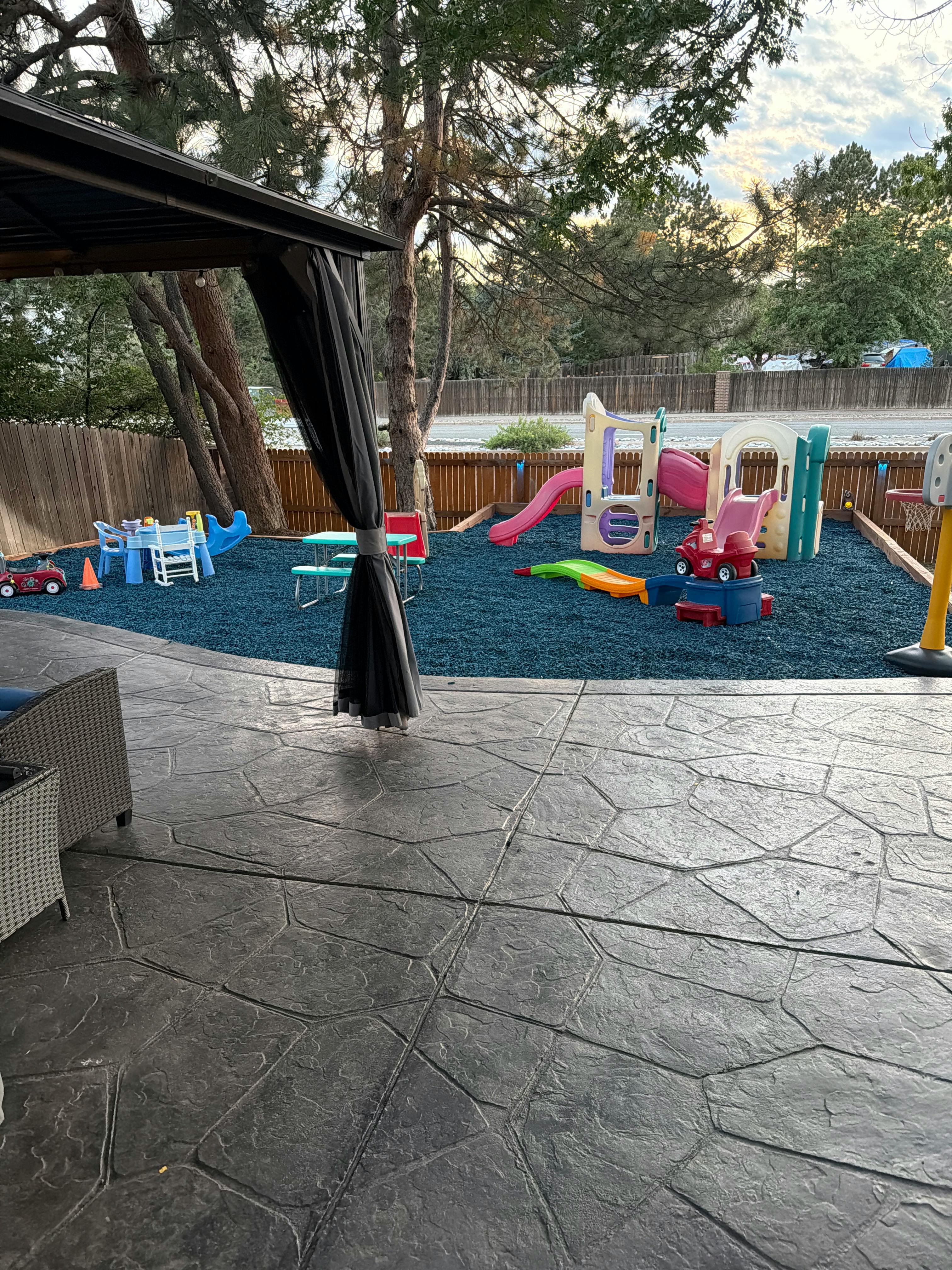 Plastic playground equipment on a blue rubber surface in a backyard