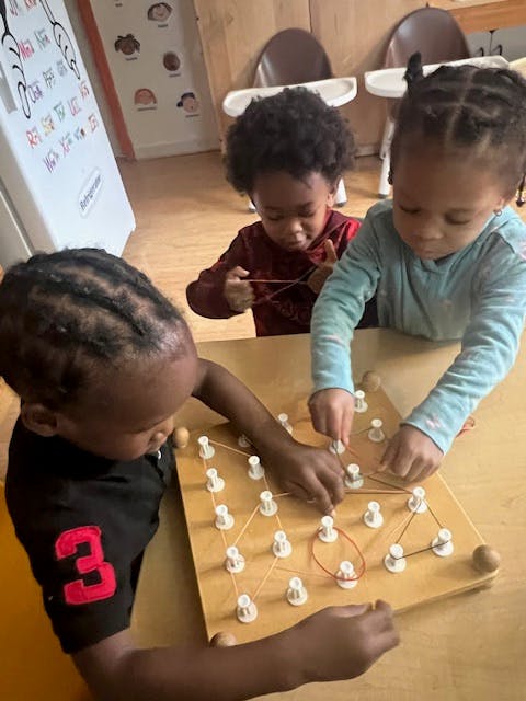 Three children playing with a geoboard and rubber bands