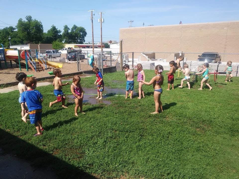 Children playing in sprinklers on a grassy field