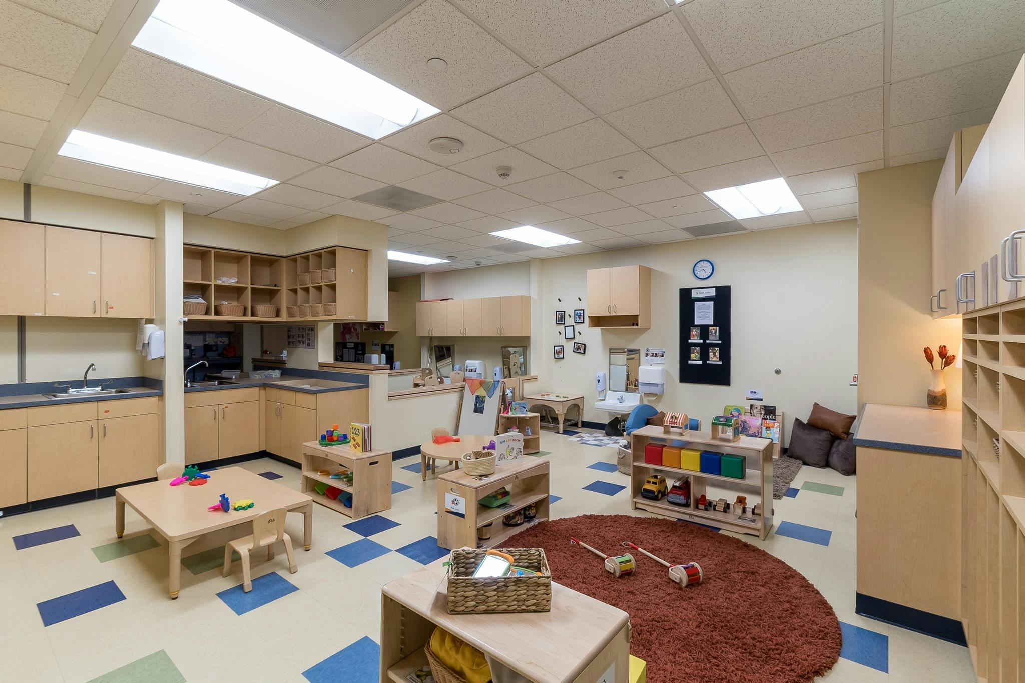 Empty classroom with small tables, chairs, and shelves with cubbies and shelves