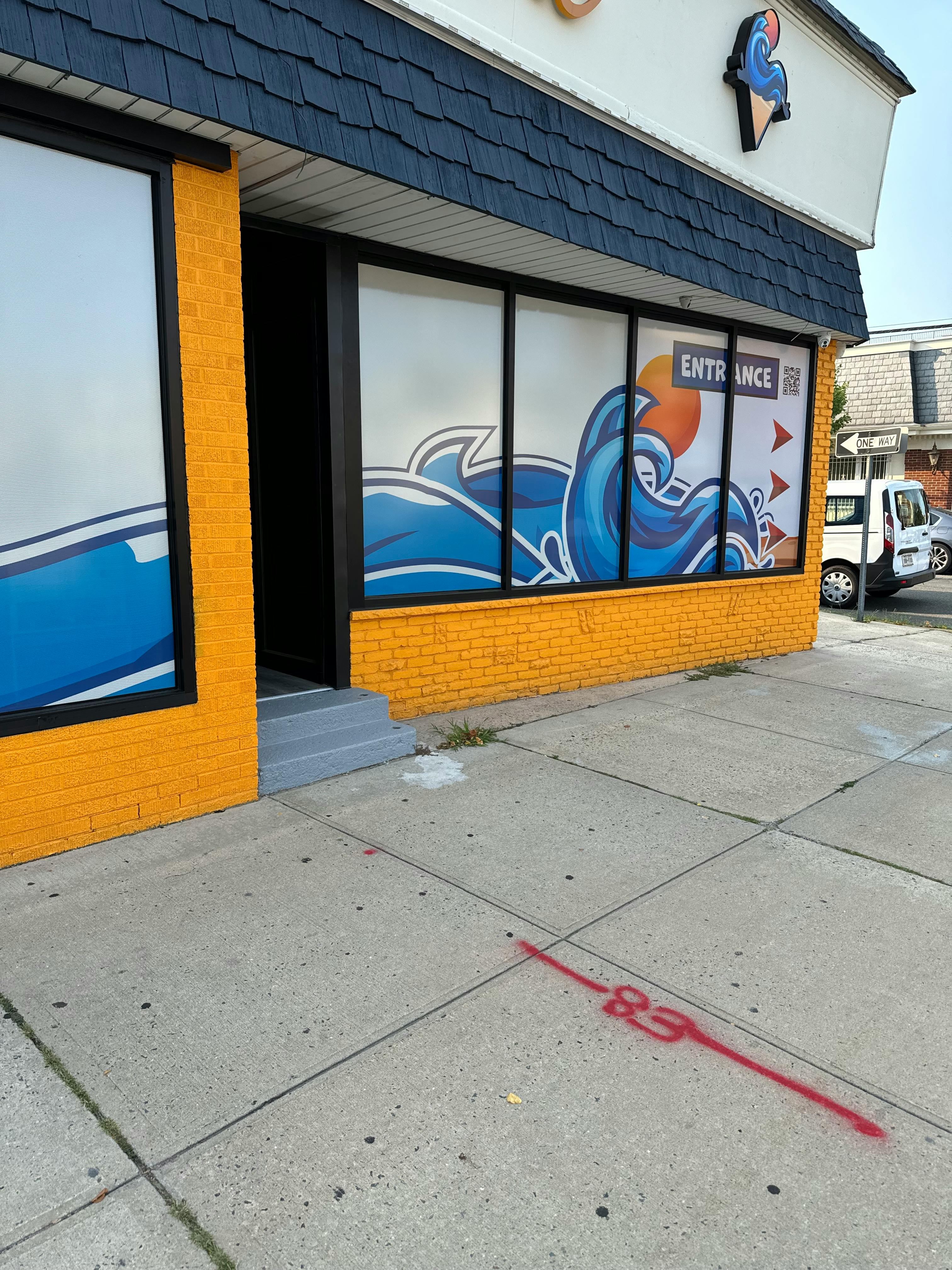 Storefront with blue wave graphics on windows and "ENTRANCE" sign