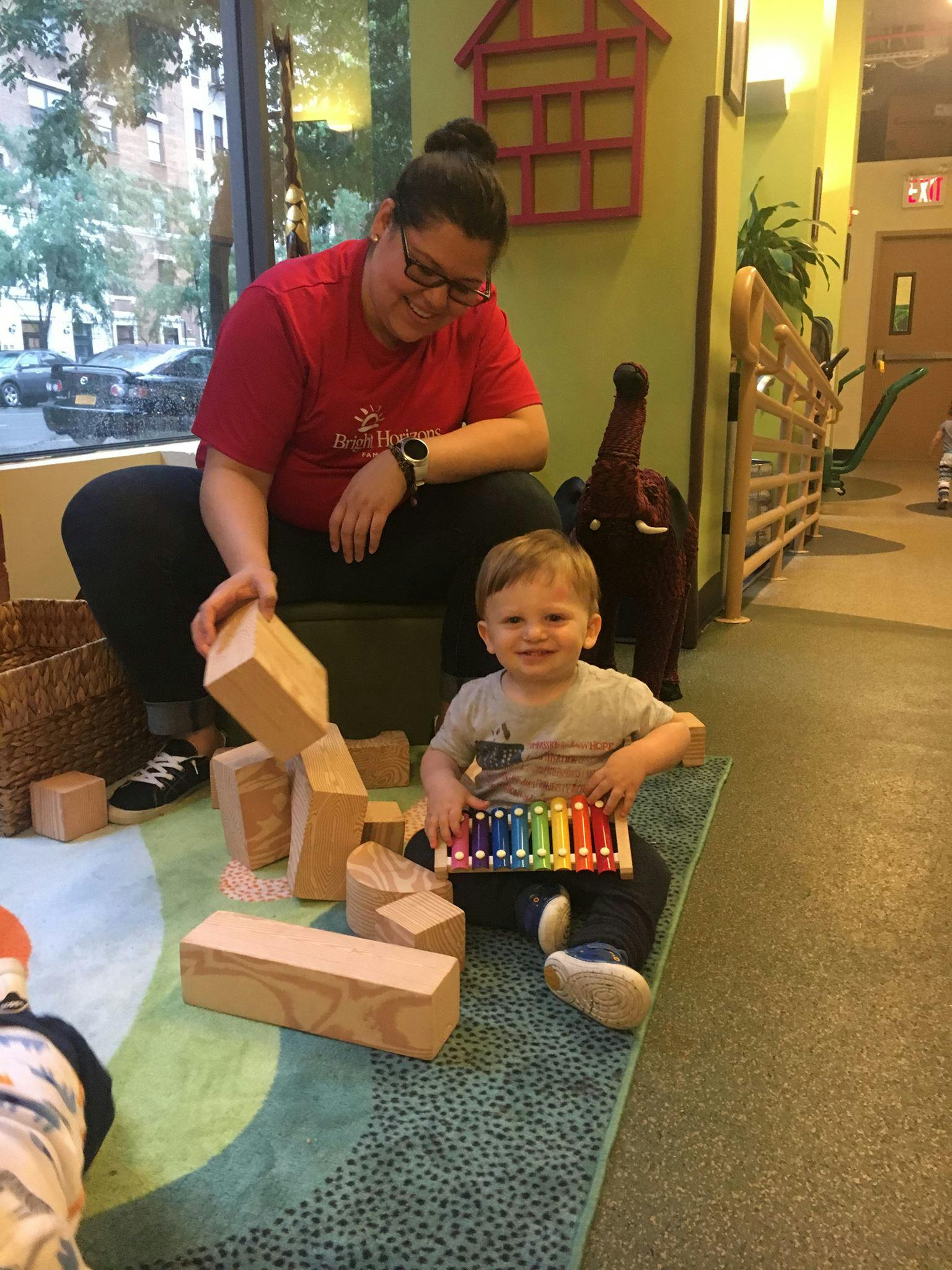 Person and child playing with blocks and a xylophone