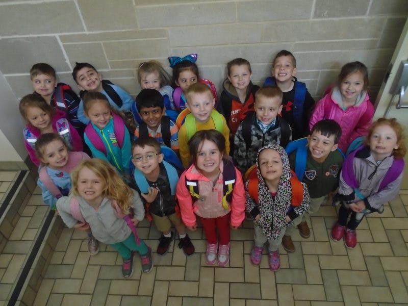 Group of children standing on a tiled floor looking up