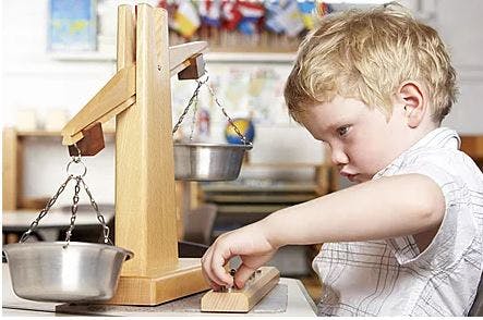 Child playing with a wooden balance scale