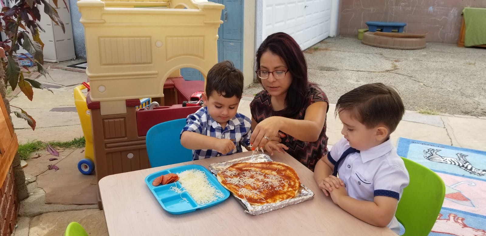 Person and two children at a table with pizza