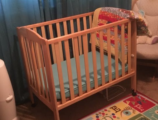 Wooden crib with a blue mattress and colorful blanket