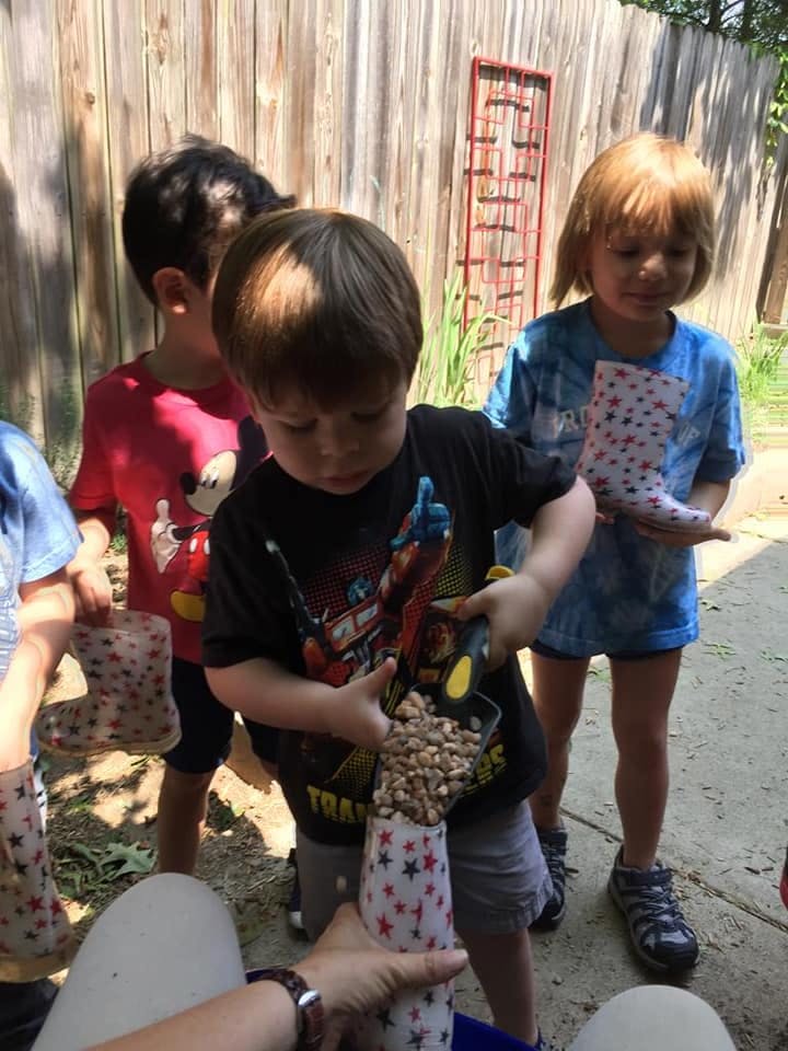 Children pouring small rocks into paper tubes
