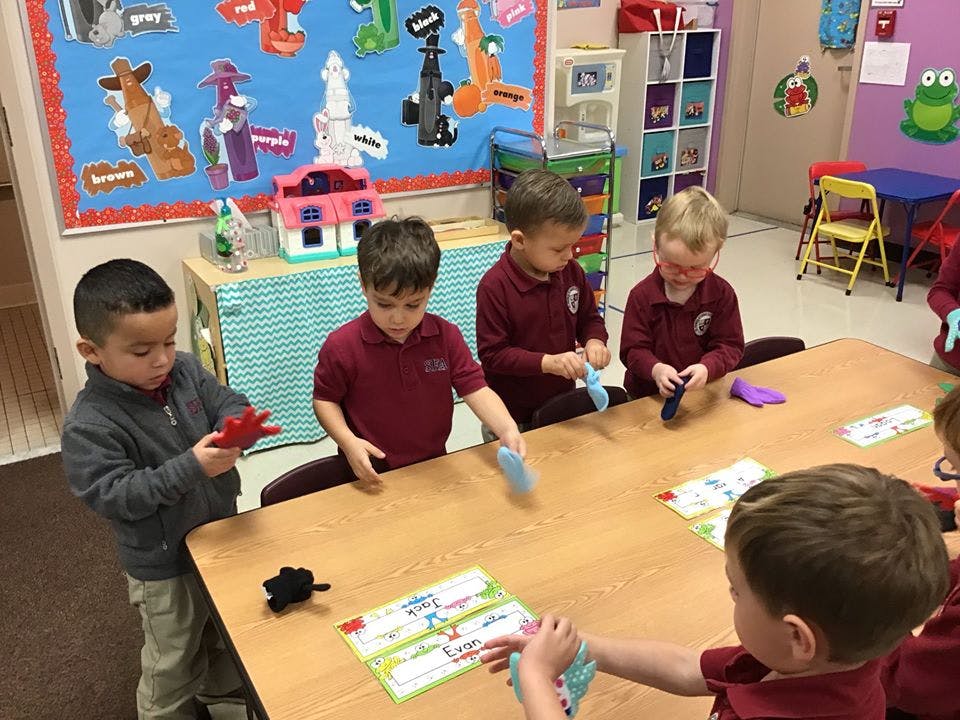 Children at a table playing with objects in a classroom