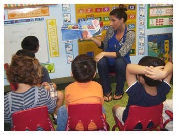 Person reading a book to children in a classroom