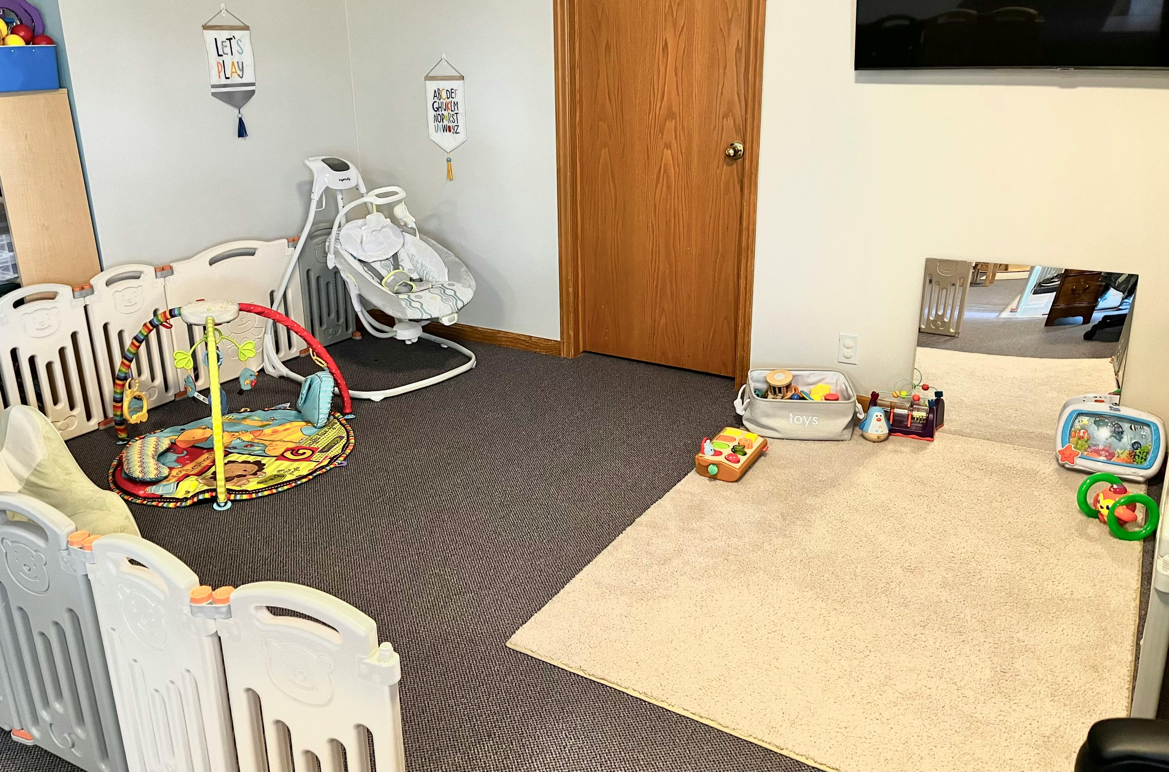 Playroom with baby swing, play mat, and toys on a rug with a rug and toys