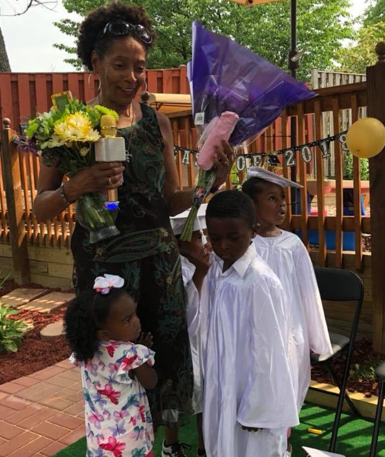 Person holding flowers and children in graduation gowns