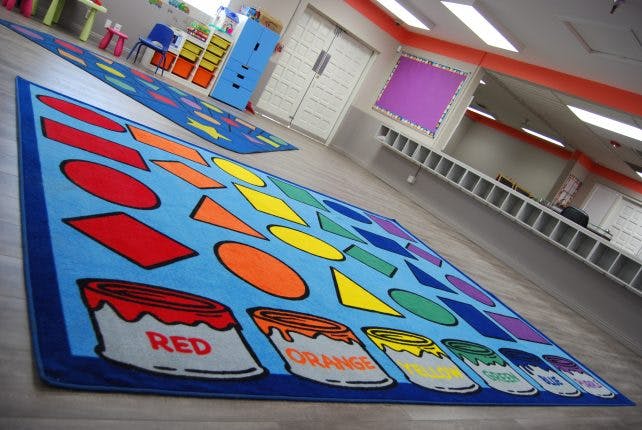 Classroom rug with shapes and paint cans labeled with colors