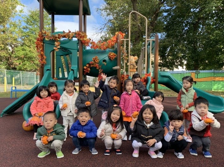 Children holding small pumpkins on a playground