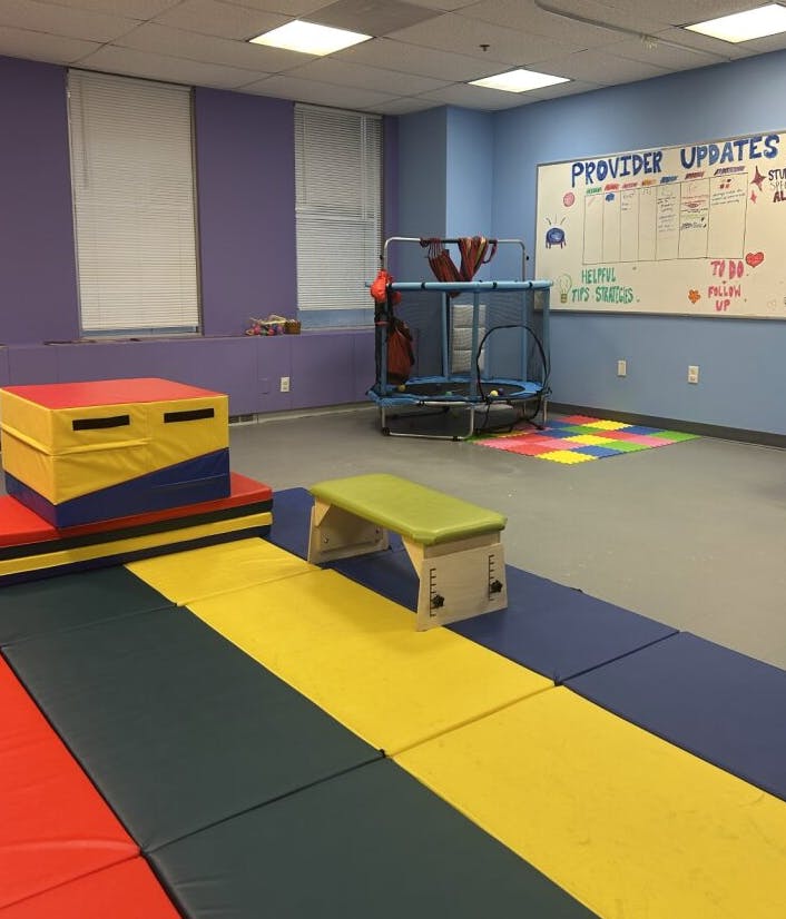 Indoor play area with mats, a trampoline, and a whiteboard with "PROVIDER UPDATES"