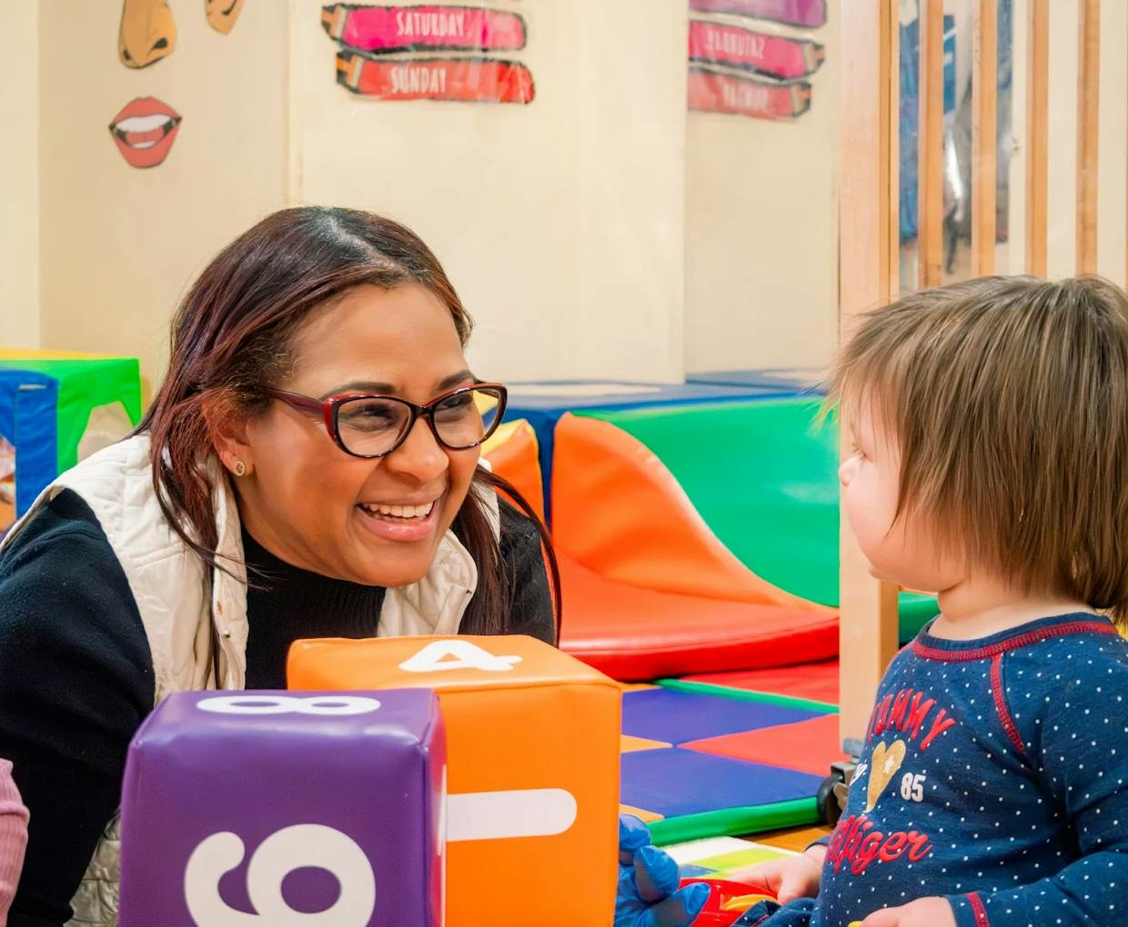 Adult and child playing with soft numbered blocks in a classroom