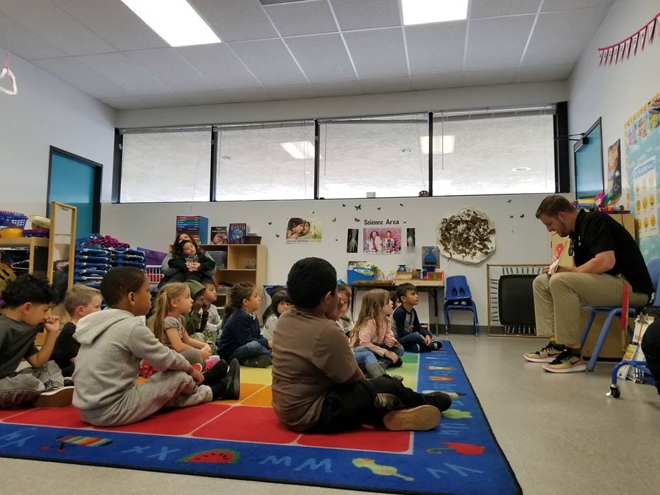 Adult reading to children sitting on a rug in a classroom