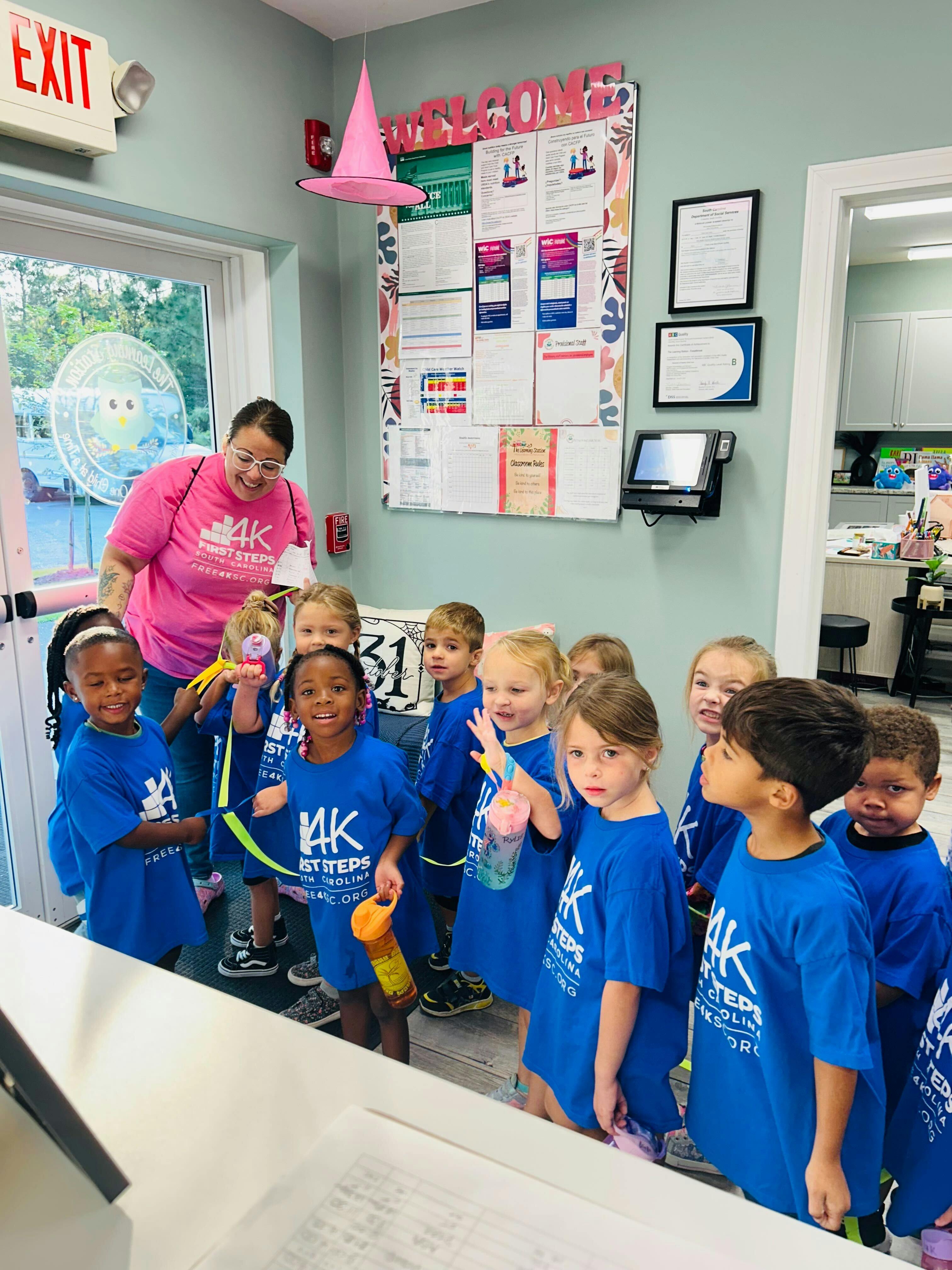Adult and group of children in blue shirts in a classroom