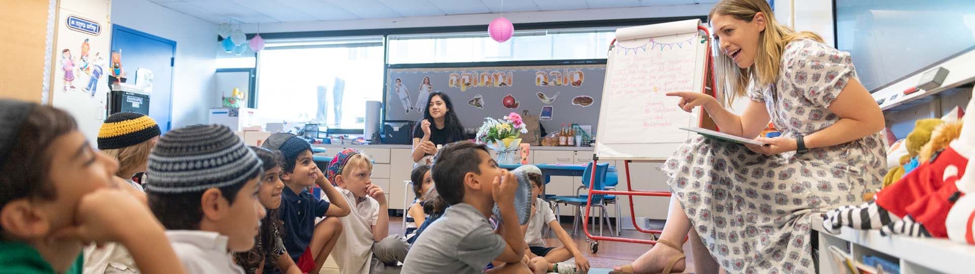 Teacher reading to a group of children seated on the floor in a classroom
