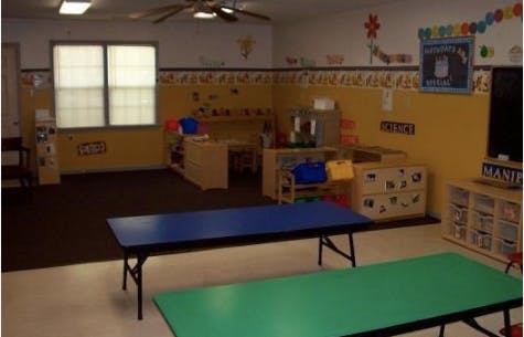 Empty classroom with yellow walls, tables, and storage units