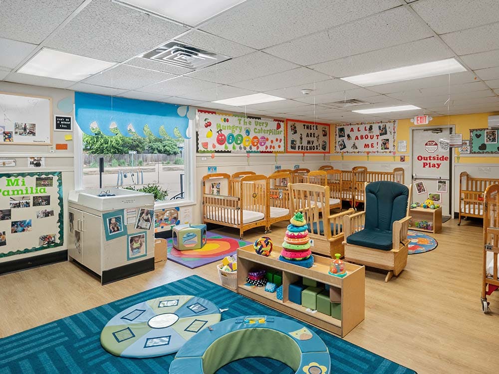 Classroom with multiple cribs, a changing station, and play mats