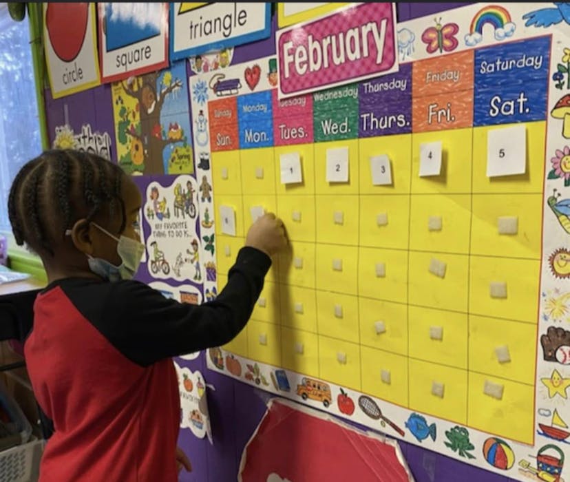 Child placing a number on a February calendar in a classroom
