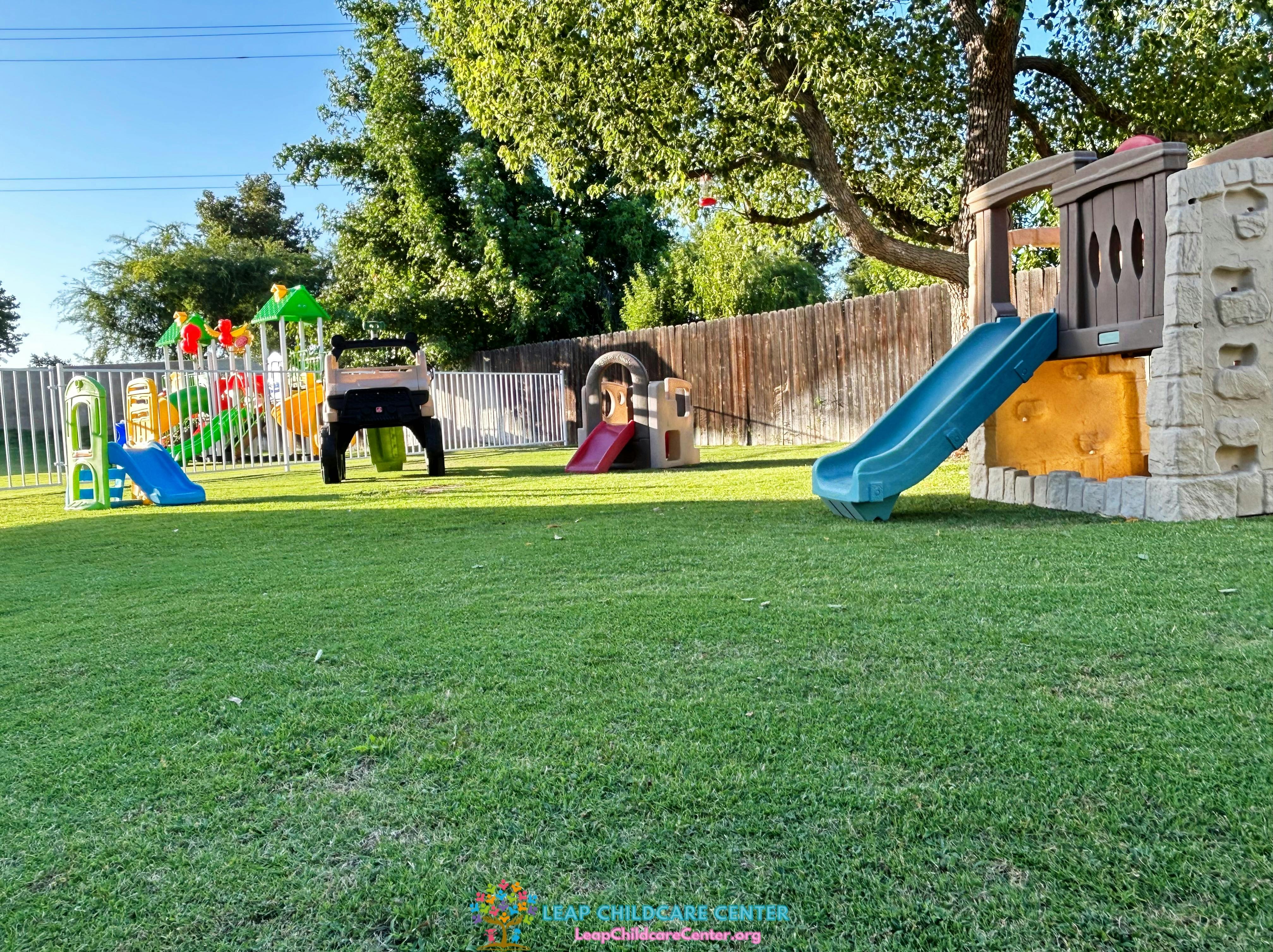 A backyard playground with multiple slides, climbing structures, and a toy car