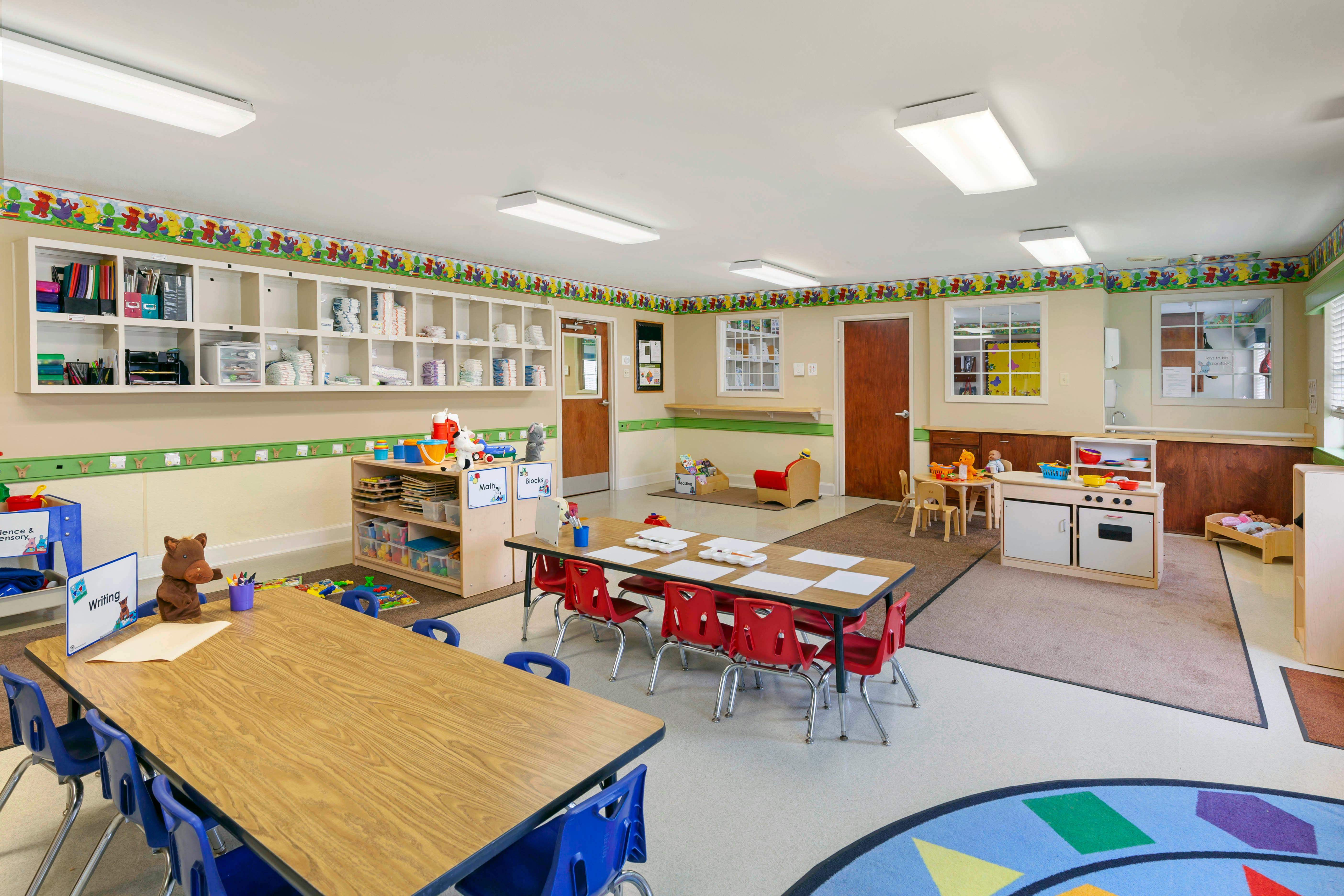 Classroom with tables, chairs, shelving units, and play areas
