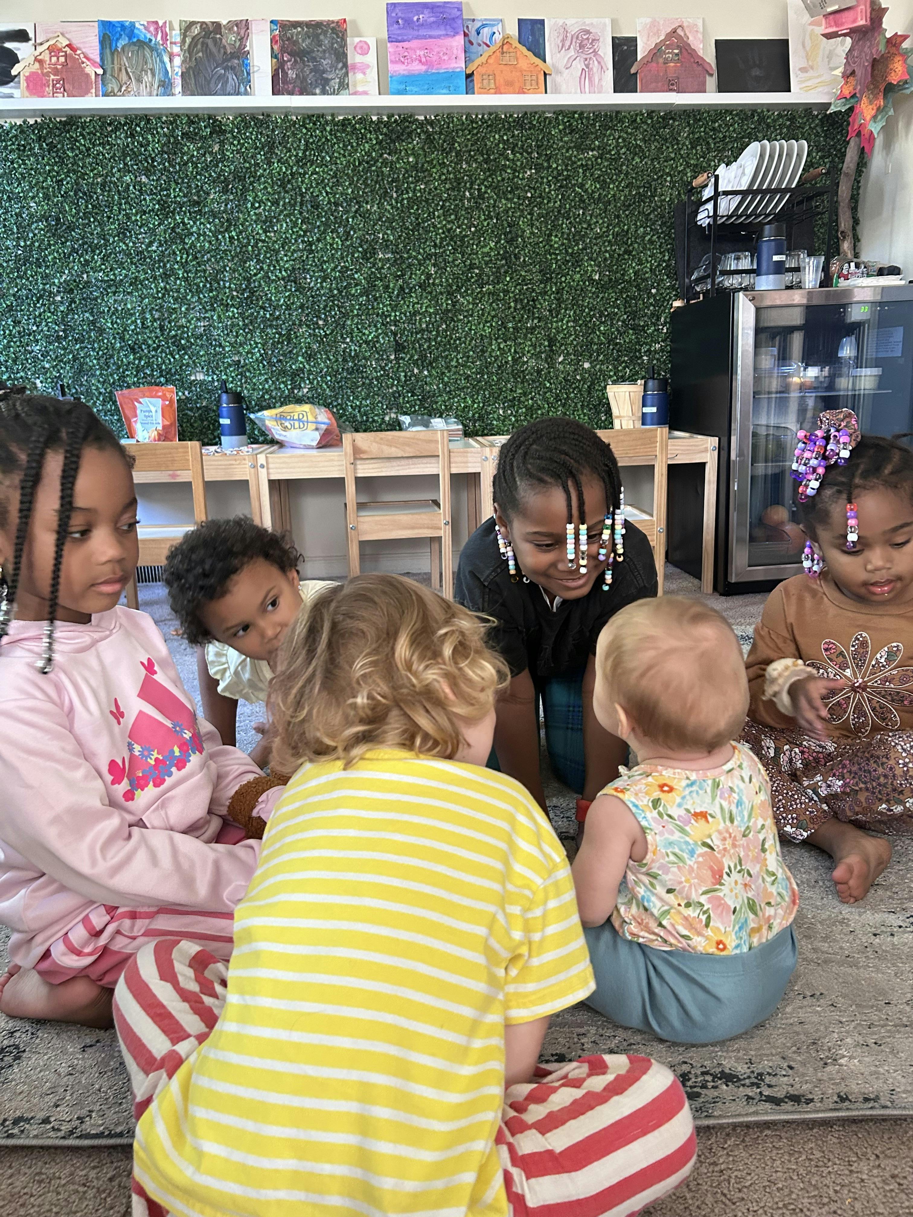 Five children playing on a carpeted floor in a classroom