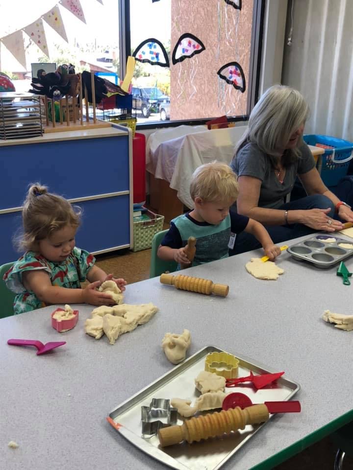 Adult and two children playing with dough at a table