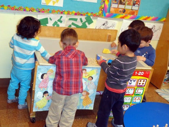 Children playing at a sand table in a classroom
