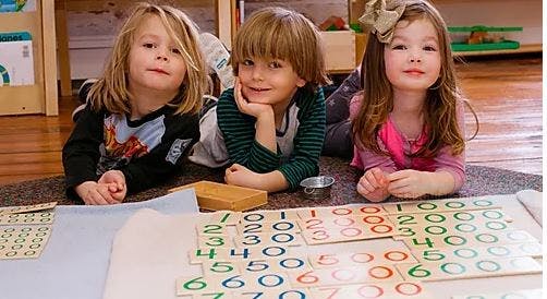 Three children lying on floor with number cards