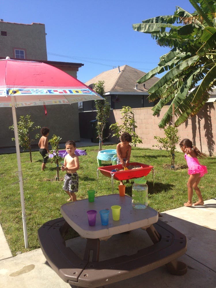 Children playing in a backyard with water toys and an umbrella