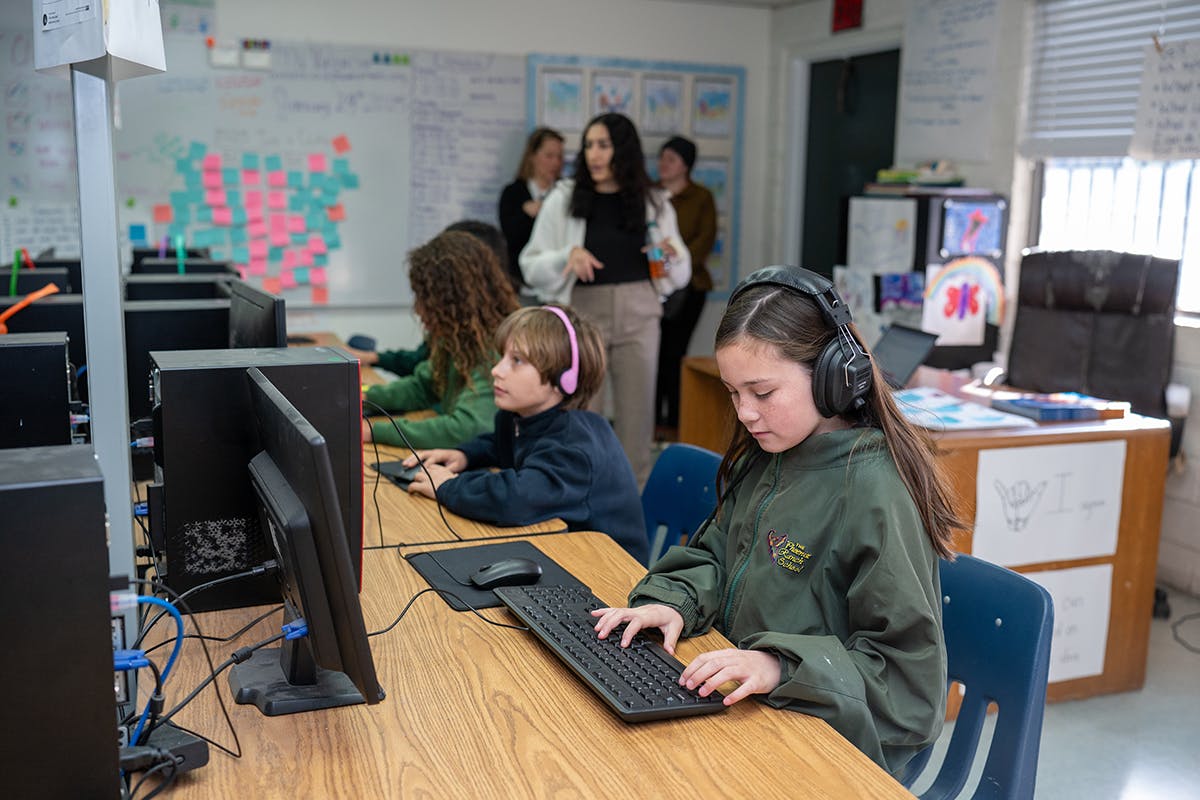 Children in a classroom using computers with headphones