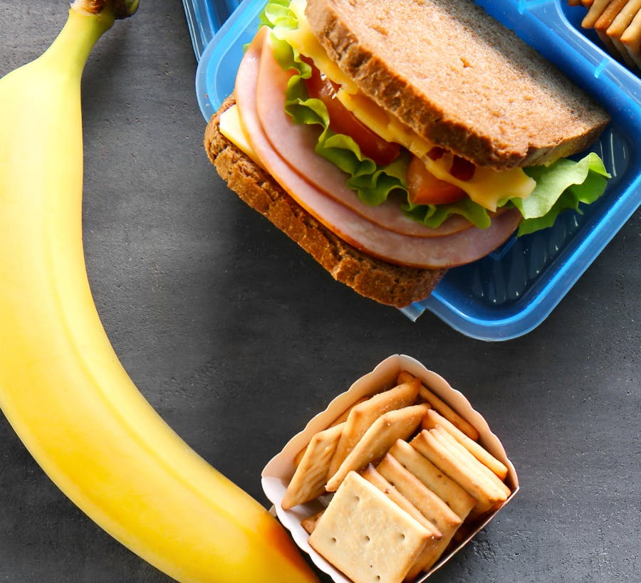 Banana, sandwich in a blue lunchbox, and crackers