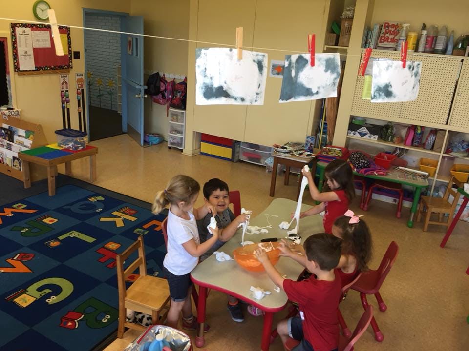Children playing with a sensory activity at a table in a classroom